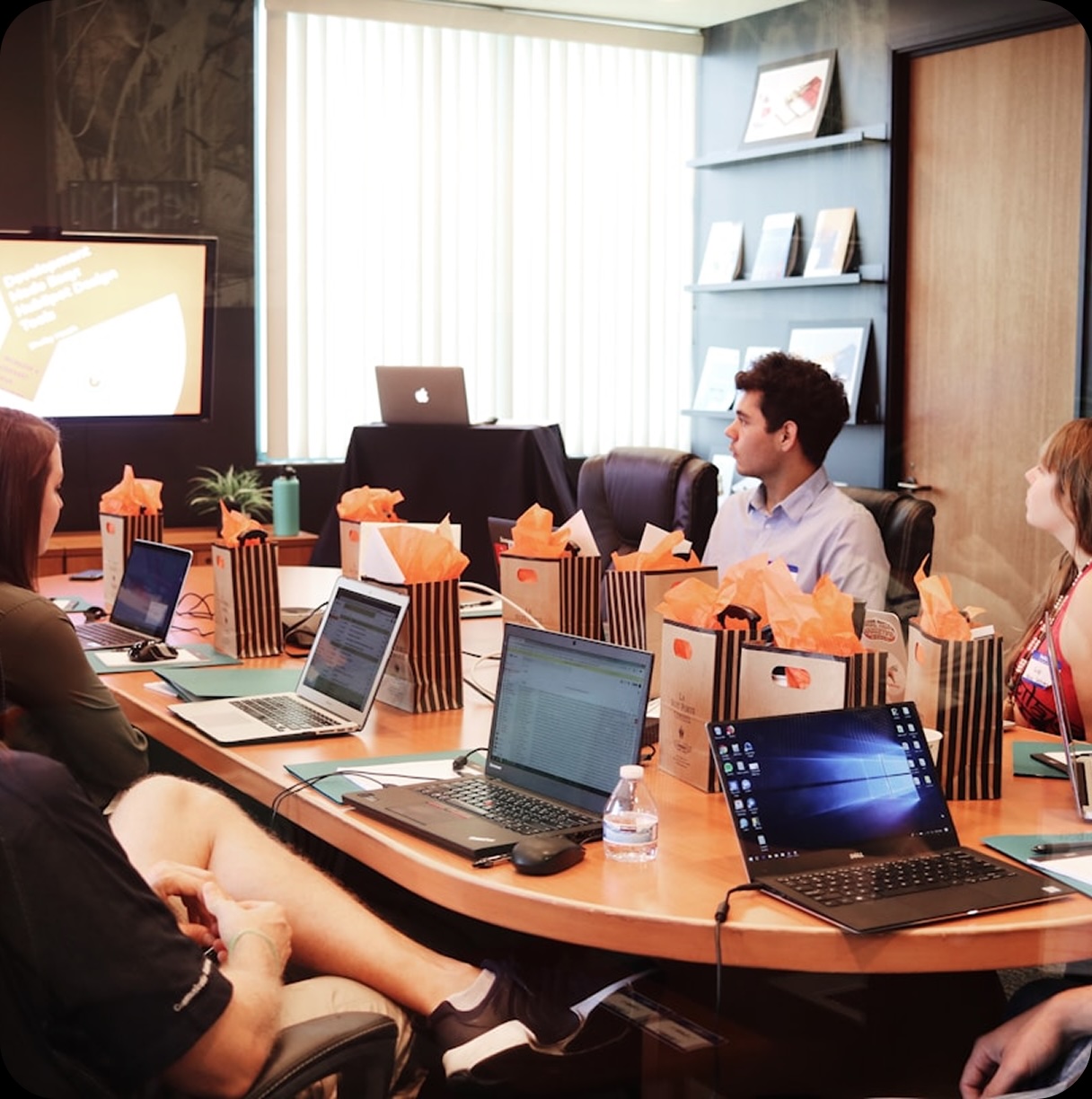 Collaborative team working around a wooden table with laptops